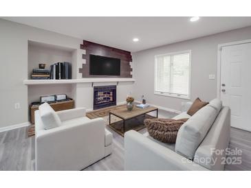 Comfortable living room featuring a fireplace with mounted TV and modern white furniture at 1847 J Julian Ln # A, Charlotte, NC 28208