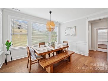 Bright dining area features a wooden table, bench, chairs, and large windows overlooking the green landscape at 528 Rock Skip Way, Fort Mill, SC 29708