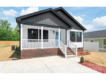 Charming home with a covered porch, brick foundation, white railings, and a bright blue front door at 640 Central Nw Dr, Concord, NC 28027