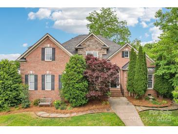 Beautiful brick home with a stone facade, lush landscaping, and a welcoming walkway at 8905 Landsdowne Ave, Harrisburg, NC 28075