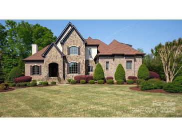 Beautiful stone and brick home with manicured lawn, lush landscaping, and a classic, timeless design at 1304 Lookout Cir, Waxhaw, NC 28173