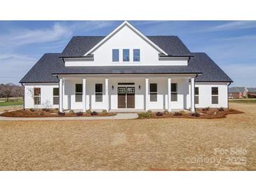 Stunning white farmhouse featuring a charming front porch with classic columns and a double door entrance at 1706 Ruben Rd, Monroe, NC 28112
