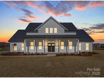 Stunning two-story home featuring a covered front porch and a manicured lawn at sunset at 1706 Ruben Rd, Monroe, NC 28112