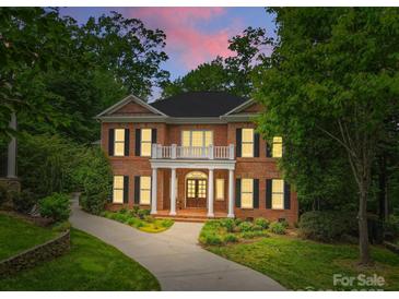 Elegant two-story brick home featuring white columns, balcony, dark shutters and a beautifully landscaped front yard at 1806 Asbury Hall Ct, Charlotte, NC 28209