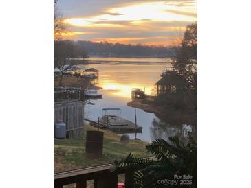 Picturesque lake view with a stunning sunset, private docks, and calm waters reflecting the colorful sky at 209 Woodstream Cir, Mooresville, NC 28117