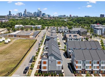 An aerial view shows a row of modern townhomes with the skyline of Charlotte, North Carolina, in the background at 2111 Isom St, Charlotte, NC 28208