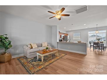 Open-concept living area with wood floors, a neutral sofa, access to the kitchen, and plenty of natural light at 233 E Waterlynn Rd # B, Mooresville, NC 28117
