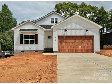New construction home with white siding, a black roof, a wooden garage door, and an unfinished yard at 418 W Westview St, Gastonia, NC 28052