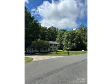 Charming two-story home with a lush green lawn and mature trees in a tranquil setting at 7531 Linda Lake Dr, Charlotte, NC 28215