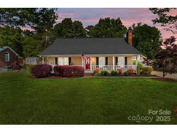 Charming single-story home with a well-manicured lawn, covered porch, and traditional American flag at 806 Mcgregor Ne Dr, Concord, NC 28025