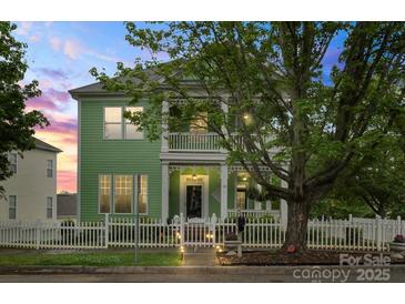 Inviting two-story home with a spacious porch and balcony, framed by lush greenery and a twilight sky at 136 Water Oak Dr, Mooresville, NC 28117