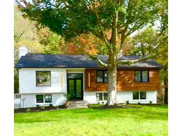 Charming exterior featuring manicured lawn, black framed windows, wood and white accents and mature trees at 200 Kimrod Ln, Charlotte, NC 28270