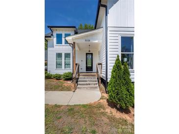 Charming home entrance features wooden steps, glass-paneled door, and a well-maintained landscape at 5028 Lewis Rd, Gastonia, NC 28052