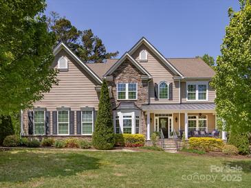 Beautiful two-story home with a stone facade, covered porch, manicured lawn, and mature trees at 10716 Meg Meadow Dr, Mint Hill, NC 28227