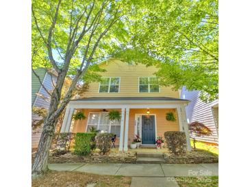 Charming yellow two-story home with a inviting front porch and lush landscaping at 240 Faust Rd, Davidson, NC 28036