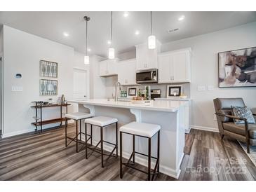 Bright, all-white kitchen features pendant lighting, breakfast bar with seating, and stainless steel appliances at 2415 Hedgecliff Rd, Kannapolis, NC 28025