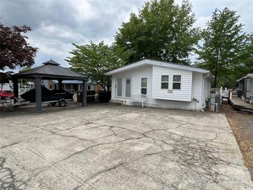 Quaint white house with boat parking, featuring a covered jet ski and spacious concrete driveway at 101 Dogwood Cir, New London, NC 28127