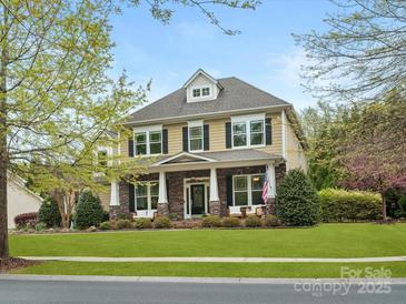 Charming two-story home featuring a covered front porch with stone accents, and a well-maintained lawn at 1515 Millbridge Pkwy, Waxhaw, NC 28173