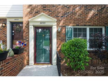 Inviting brick townhome entrance features a classic door with decorative trim and a well-maintained landscape at 8835 Hunter Ridge Dr, Charlotte, NC 28226