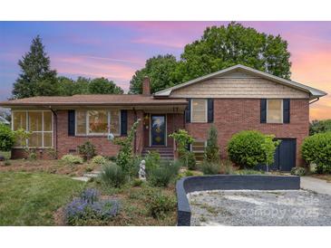 Charming brick home featuring a landscaped front yard and a cozy sunroom addition at dusk at 910 E Center Ave, Mooresville, NC 28115