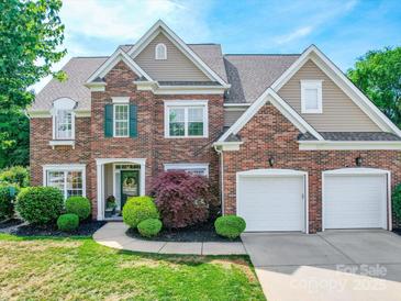 Traditional brick home featuring a two-car garage, manicured lawn, and mature landscaping at 1103 Cooper Ln, Indian Trail, NC 28079