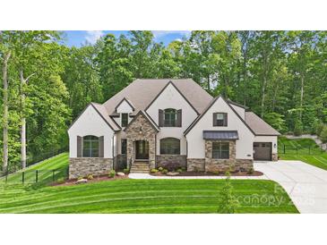 Stunning exterior of a two-story home with stone accents, neutral stucco, and a professionally landscaped yard at 13106 Bien Ct, Huntersville, NC 28078