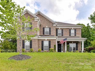Charming brick two-story home with black shutters, manicured lawn, and American flag displayed by front door at 2369 Baxter Se Pl, Concord, NC 28025