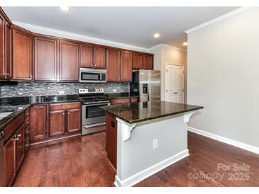 Kitchen featuring dark cabinets, granite countertops, stainless steel appliances, and a kitchen island at 2369 Baxter Se Pl, Concord, NC 28025