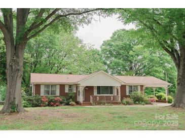 Charming brick home with covered porch and carport, surrounded by lush trees and landscaping at 2412 Wedgewood Dr, Salisbury, NC 28146