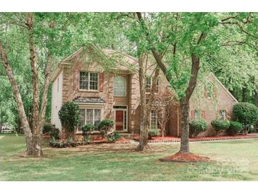 Charming two-story brick home featuring a landscaped front yard, mature trees and shuttered windows at 4410 Laurel Twig Ct, Charlotte, NC 28215
