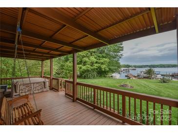 Covered porch with a porch swing, hot tub and beautiful views of the landscaped yard and lake at 7942 Vista View Dr, Sherrills Ford, NC 28673