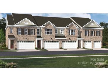 Beautiful brick townhome featuring a front-entry garage and multiple windows for ample natural light at 12033 Lavinia Ln, Charlotte, NC 28277