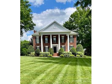 Stately brick home with white columns and manicured lawn creates a grand and inviting curb appeal at 1721 White Pond Ln, Waxhaw, NC 28173