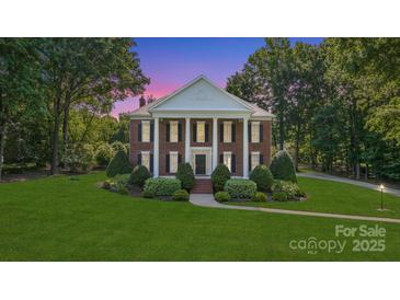 Stately brick home with white columns, black shutters, manicured lawn, and mature trees at 1721 White Pond Ln, Waxhaw, NC 28173