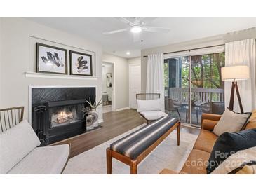 Cozy living room with fireplace, ceiling fan, hardwood floors, and a sliding glass door to the balcony at 611 Olmsted Park Pl # C, Charlotte, NC 28203