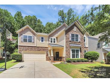 Beautiful two-story home with stone and siding exterior, attached garage, and basketball hoop at 9930 Karras Commons Way, Matthews, NC 28105