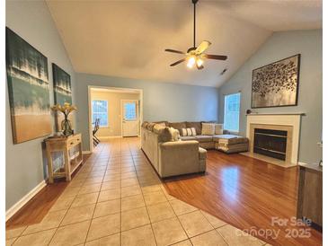 Spacious living room featuring a fireplace, ceiling fan, and hardwood flooring transitioning to tile near the dining area at 10408 Milstead Ct, Charlotte, NC 28215