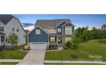 Charming two-story home featuring a stone facade, covered porch, and well-manicured lawn at 14218 Morningate St, Huntersville, NC 28078