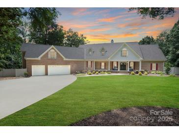 Charming brick home features a manicured lawn, mature trees, and an attached two-car garage at 17112 Green Dolphin Ln, Cornelius, NC 28031