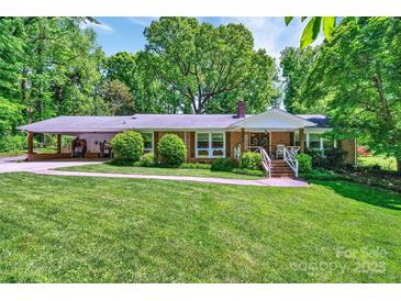 Charming brick ranch home with lush lawn, carport, and inviting front porch nestled among mature trees at 3810 Springway Dr, Gastonia, NC 28056