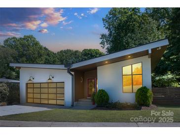 Stylish home showcasing a modern design, glass garage door, and manicured lawn at 4211 Mantle Ct, Charlotte, NC 28205