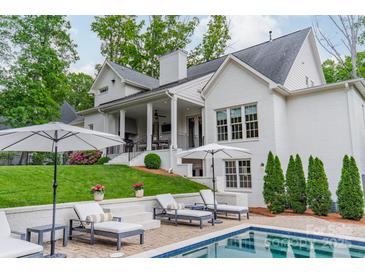 A pristine backyard pool and patio is flanked by lounge seating and manicured landscaping in this relaxing outdoor oasis at 331 Anthony Cir, Charlotte, NC 28211