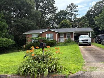 Charming brick home with a well-manicured lawn, colorful flowers, and a convenient carport at 910 Mcgowan Rd, Shelby, NC 28150