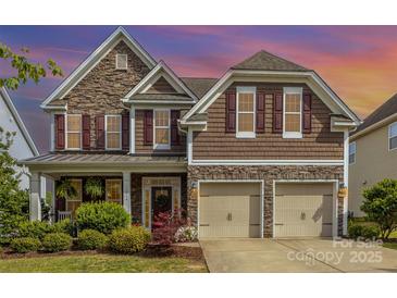 Charming two-story home featuring a stone and shingle facade, well-manicured landscaping, and a two-car garage at 11014 Aspen Ridge Nw Ln, Concord, NC 28027