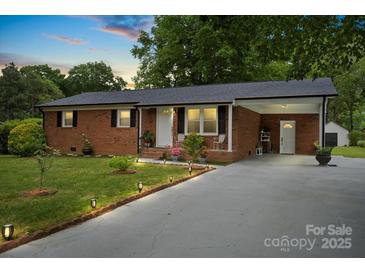 Charming brick home featuring a well-maintained lawn and a covered carport area at 324 Autumn Dr, Harrisburg, NC 28075