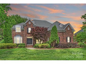 Charming brick home featuring manicured landscaping, a gray roof, and a double door entry at 5940 Four Wood Dr, Matthews, NC 28104