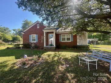 Charming brick home with a covered porch, blue shutters, and beautiful landscaping at 6585 White St, Kershaw, SC 29067