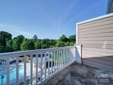 Relax on the balcony with a community pool view and wooded perimeter, perfect for unwinding outdoors at 1000 E Woodlawn Rd # 402, Charlotte, NC 28209