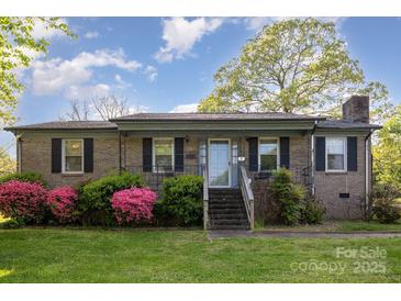 Charming brick home featuring a well-maintained lawn and flowering shrubs, creating a welcoming curb appeal at 1009 N Main St, Mount Holly, NC 28120