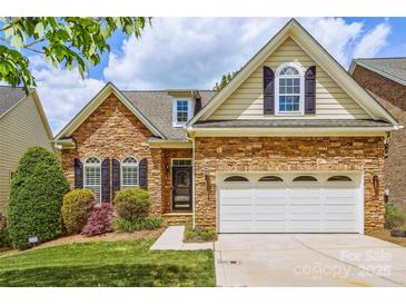 Charming stone-clad home with a two-car garage, manicured lawn, and lovely landscaping details at 1365 Winged Foot Dr, Denver, NC 28037